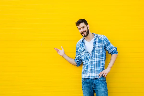 Genç mutlu adam sarı bir duvara karşı ayakta — Stok fotoğraf