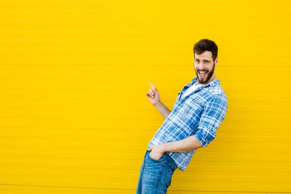 Genç mutlu adam sarı bir duvara karşı ayakta