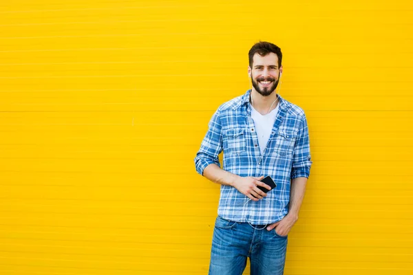 Young handsome man with headphones on yellow wall — Stock Photo, Image