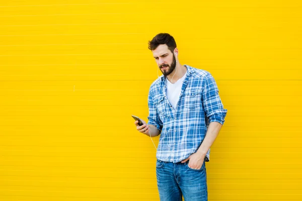 Joven hombre guapo con auriculares en la pared amarilla — Foto de Stock