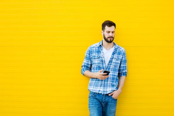 Joven hombre guapo con auriculares en la pared amarilla — Foto de Stock