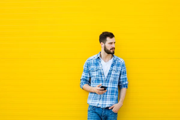 Fiatal jóképű férfi fejhallgató a sárga fal — Stock Fotó