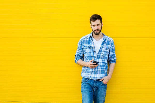 Joven hombre guapo con auriculares en la pared amarilla — Foto de Stock