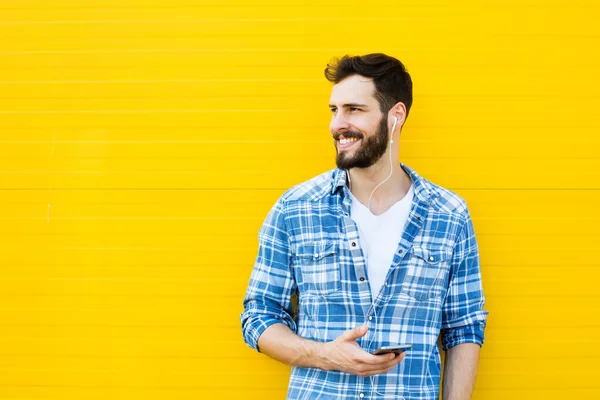 Young handsome man with headphones on yellow wall — Stock Photo, Image