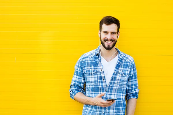Young handsome man with headphones on yellow wall — Stock Photo, Image