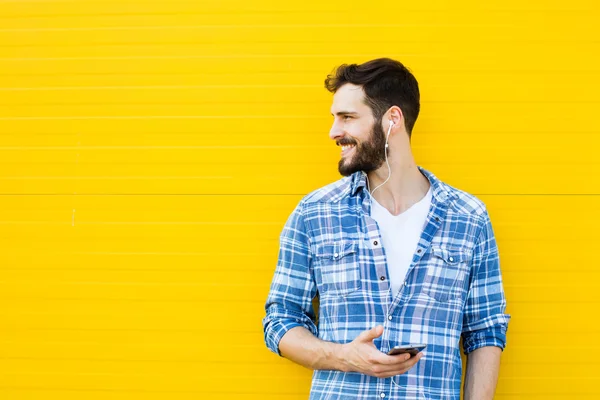 Joven hombre guapo con auriculares en la pared amarilla — Foto de Stock