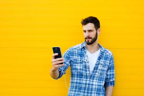 Joven hombre guapo con auriculares en la pared amarilla — Foto de Stock