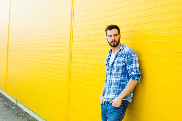 Mladý pohledný muž se sluchátky na žluté zdi — Stock fotografie