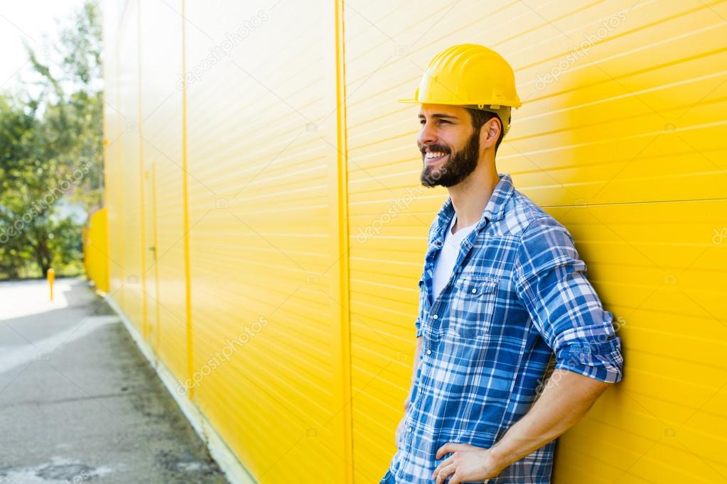 adult worker with helmet on yellow wall