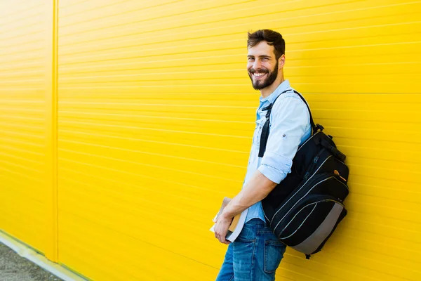 Schöner Mann mit Rucksack auf gelb — Stockfoto