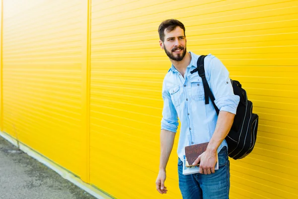 Schöner Mann mit Rucksack auf gelb — Stockfoto