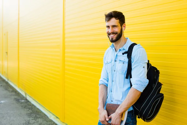 Schöner Mann mit Rucksack auf gelb — Stockfoto