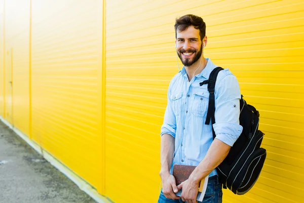 Schöner Mann mit Rucksack auf gelb — Stockfoto