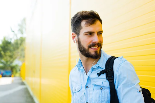 Handsome man with backpack on yellow — Stock Photo, Image