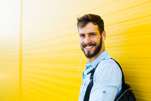 Handsome man with backpack on yellow — Stock Photo, Image