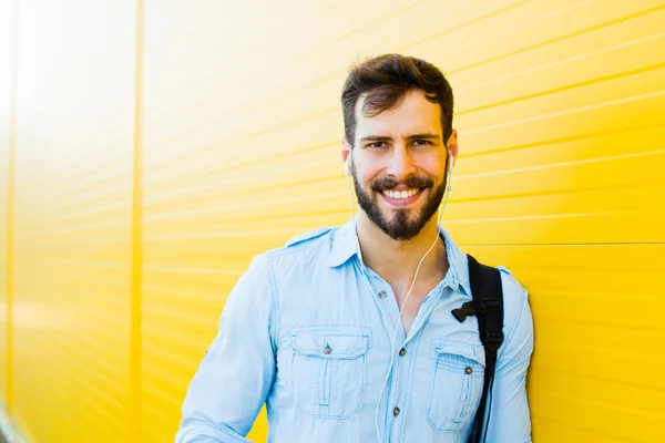 Handsome man with backpack on yellow — Stock Photo, Image