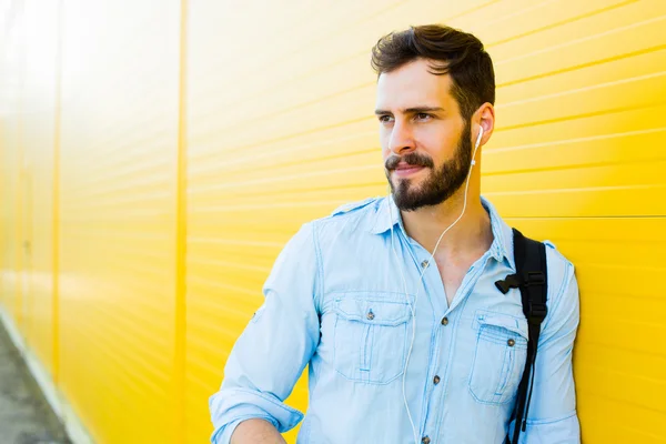 Schöner Mann mit Rucksack auf gelb — Stockfoto