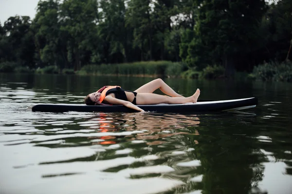 Donna sdraiata su una pedana sull'acqua — Foto Stock