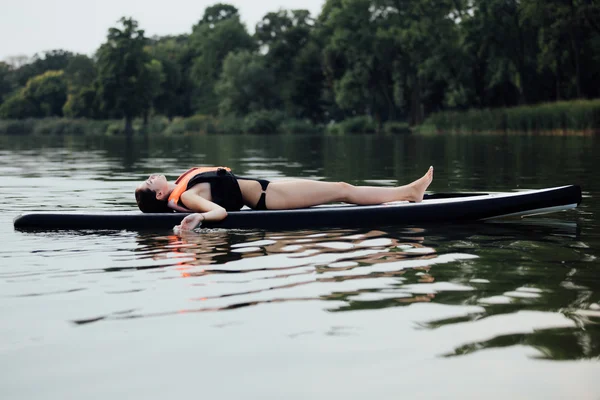 Žena ležela na desce pádlo na vodě — Stock fotografie