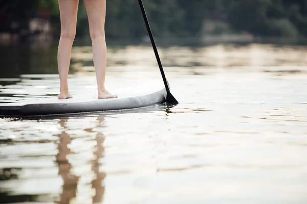 Clouse-up de uma mulher pernas em paddleboard — Fotografia de Stock