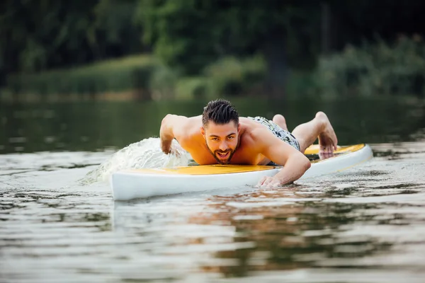 Athletic man swimming on a paddleboard — Stock Photo, Image