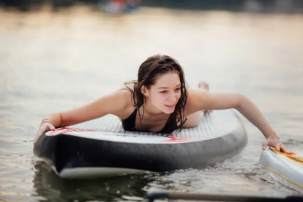 Žena ležela na desce pádlo na vodě — Stock fotografie