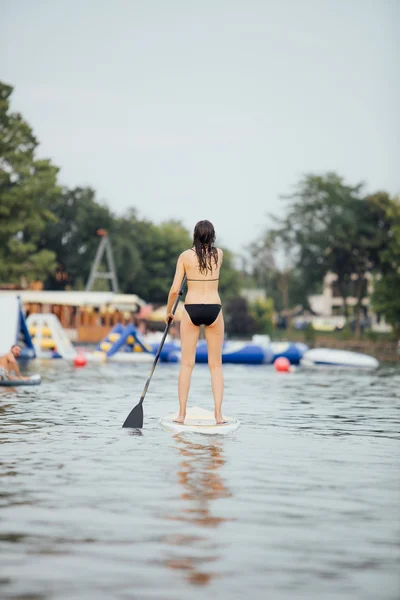 Žena, která dělá postaví pádlo na jezero obklopené stromy — Stock fotografie