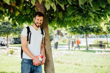 sırt çantası ve bir hediye bir ağacının yanındaki adam