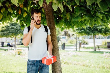 sırt çantası ve bir hediye bir ağacının yanındaki adam