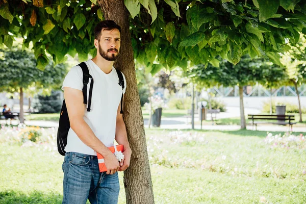 Homem com mochila e um presente ao lado de uma árvore — Fotografia de Stock