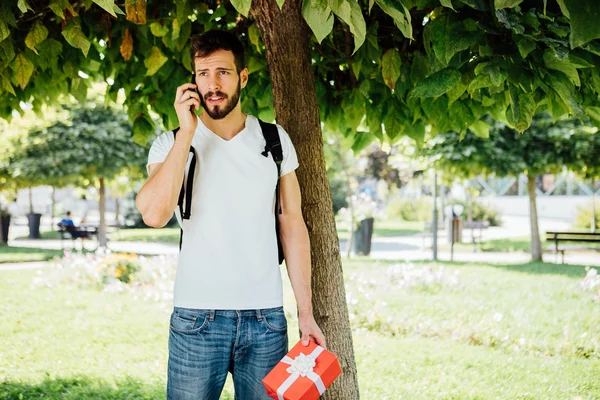 Mann mit Rucksack und Geschenk neben einem Baum — Stockfoto