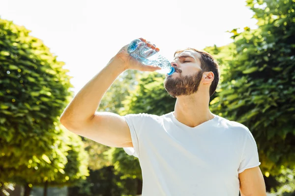 Adult man drinking water from a bottle outside — Stock Photo, Image
