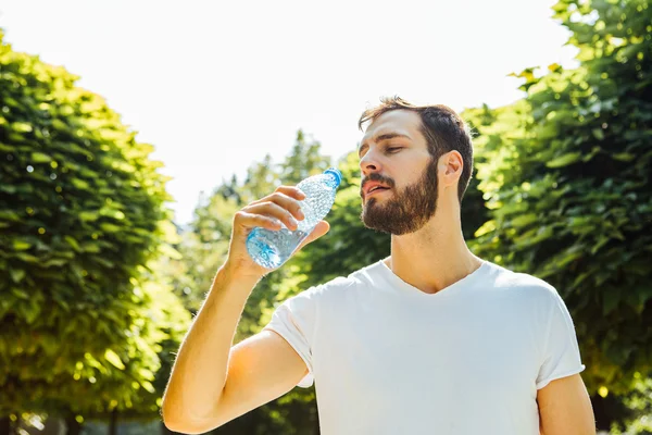 Adult man drinking water from a bottle outside — Stock Photo, Image
