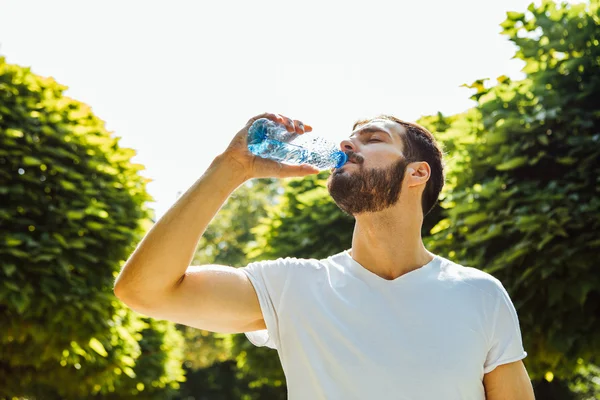 Vuxen man dricksvatten från en flaska utanför — Stockfoto