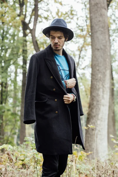 Junger Mann mit schwarzem Hut im Wald — Stockfoto