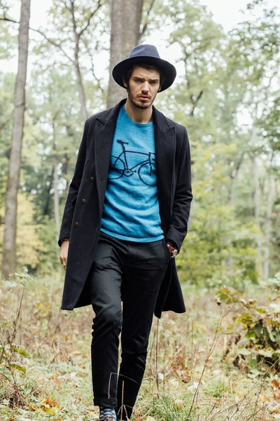 Junger Mann mit schwarzem Hut im Wald — Stockfoto