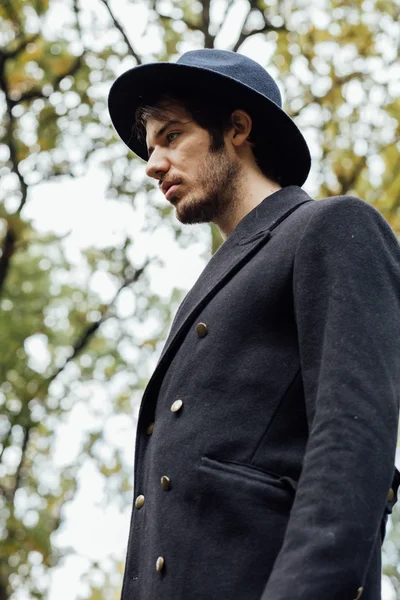 Jeune homme avec chapeau noir dans la forêt — Photo