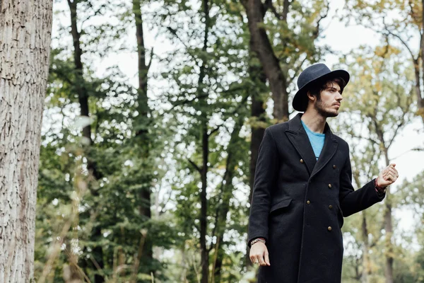 Jeune homme avec chapeau noir dans la forêt — Photo