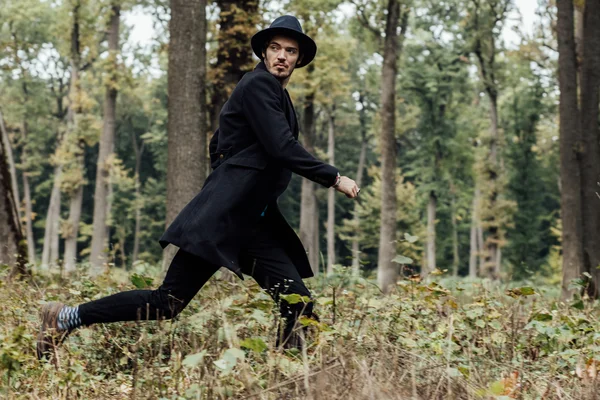 Junger Mann mit schwarzem Hut im Wald — Stockfoto