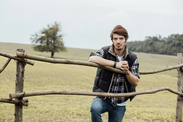 Young man next to a wooden fence — Stock Photo, Image