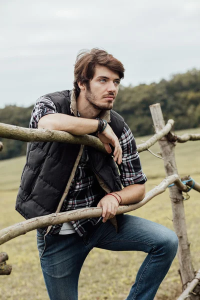 木製のフェンスの横に若い男 — ストック写真