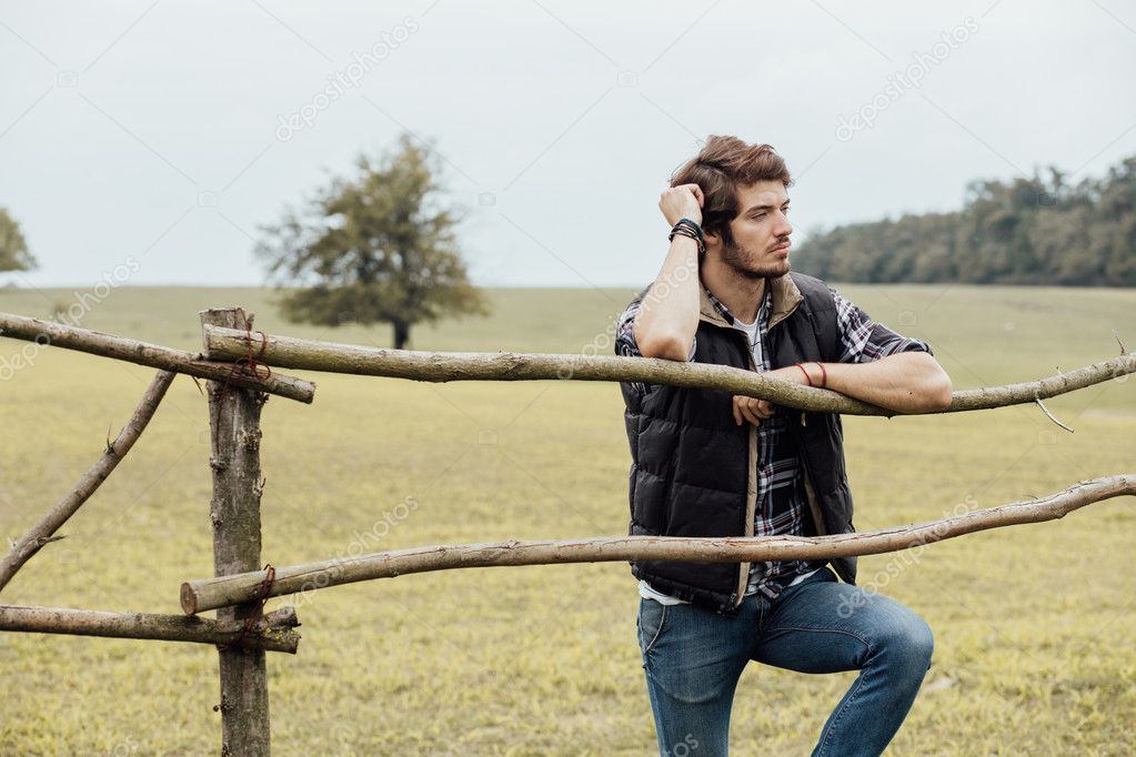young man next to a wooden fence