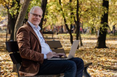 bir bankta dışında dizüstü çalışan eski iş adamları