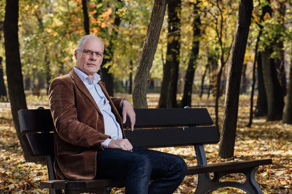 Vecchio uomo elegante seduto sulla panchina fuori — Foto Stock