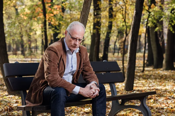 Viejo elegante hombre sentado en el banco fuera — Foto de Stock