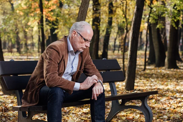 Viejo elegante hombre sentado en el banco fuera — Foto de Stock