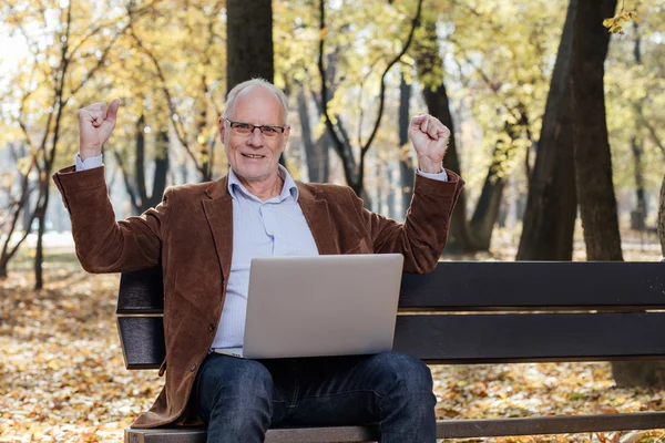 Alte Geschäftsleute, die draußen auf einer Bank am Laptop arbeiten — Stockfoto