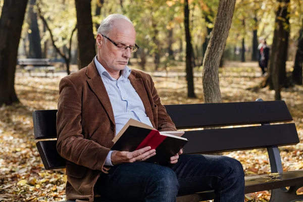 Старий елегантний чоловік читає книгу надворі — стокове фото