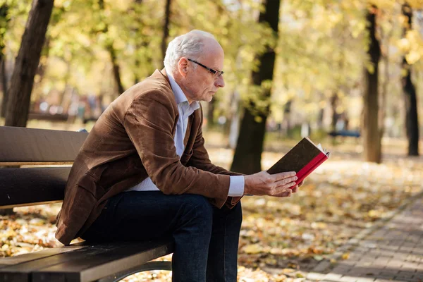Viejo hombre elegante leyendo un libro fuera — Foto de Stock