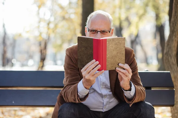 Viejo hombre elegante leyendo un libro fuera — Foto de Stock